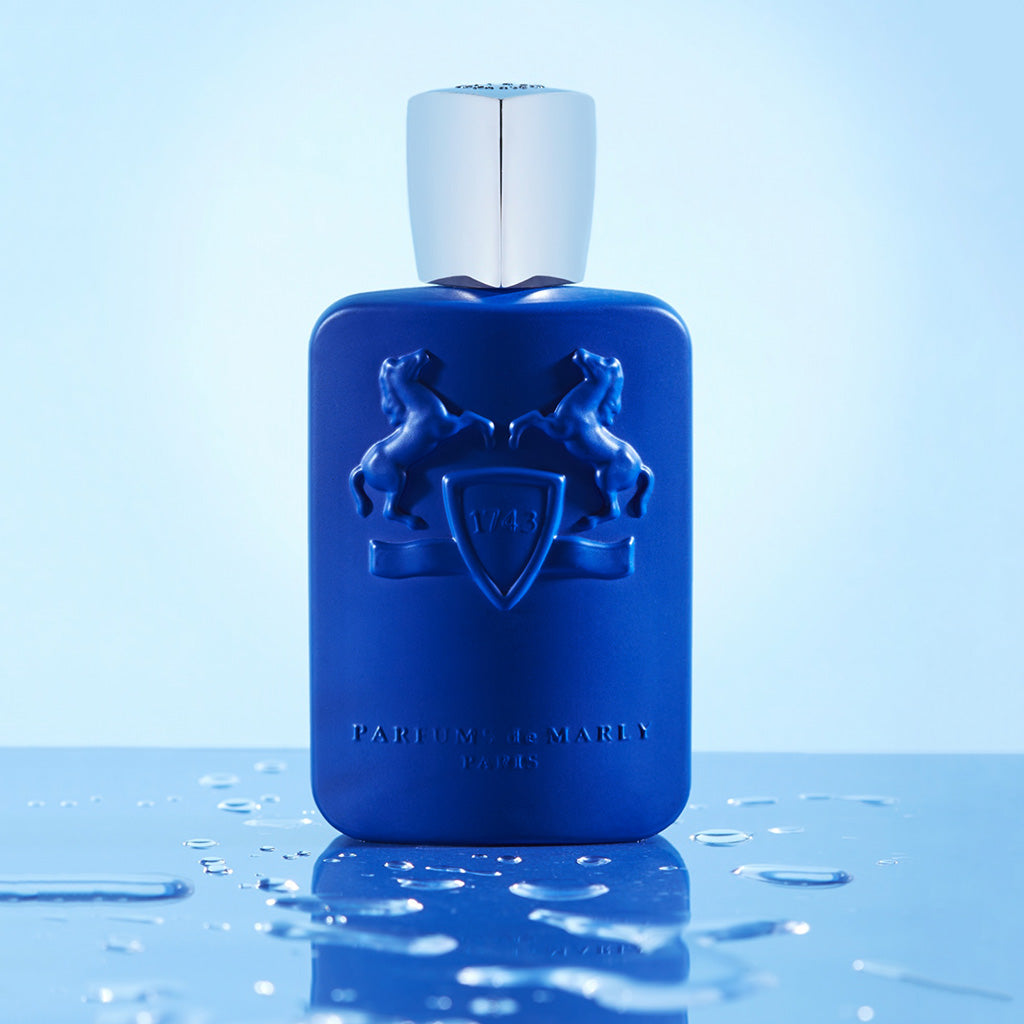 Percival by Parfums de Marly, 125ml royal blue bottle set on a reflective surface with water droplets and blue background