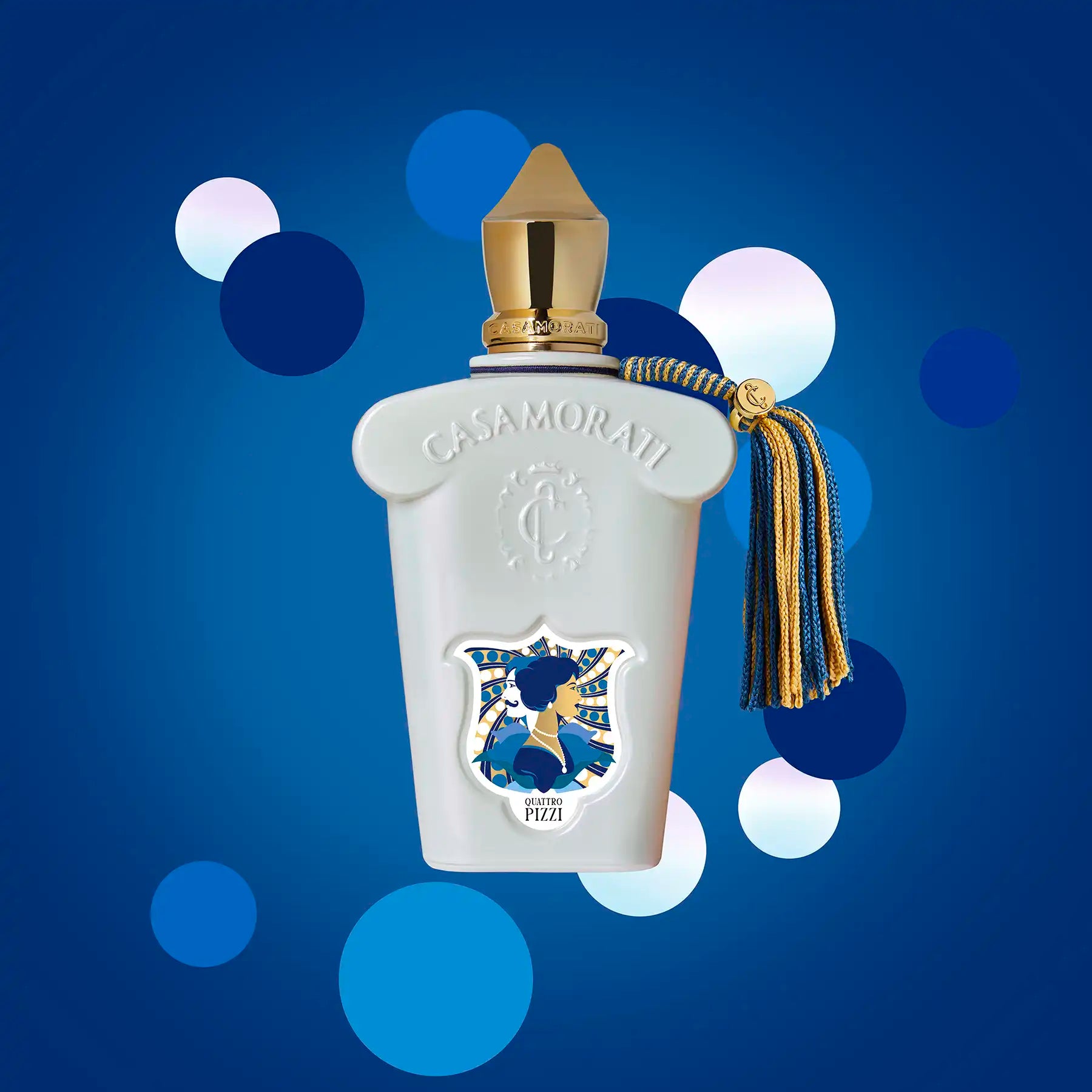 Casamorati Quattro Pizzi perfume bottle against a blue background with white circles, highlighting the bottle's design and tassel.